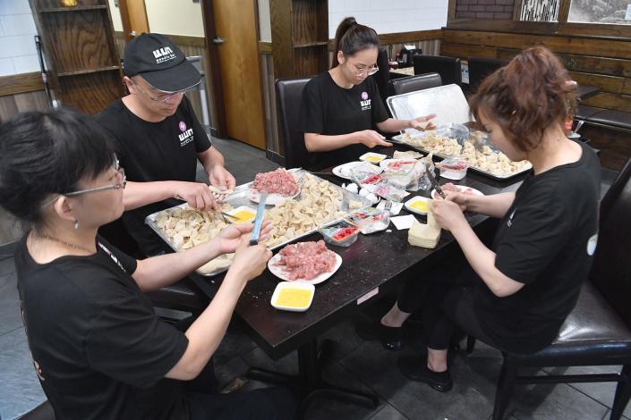 A group of employees making handmade won ton dumplings at Fun Noodle Bar, next to the Rib Crib.