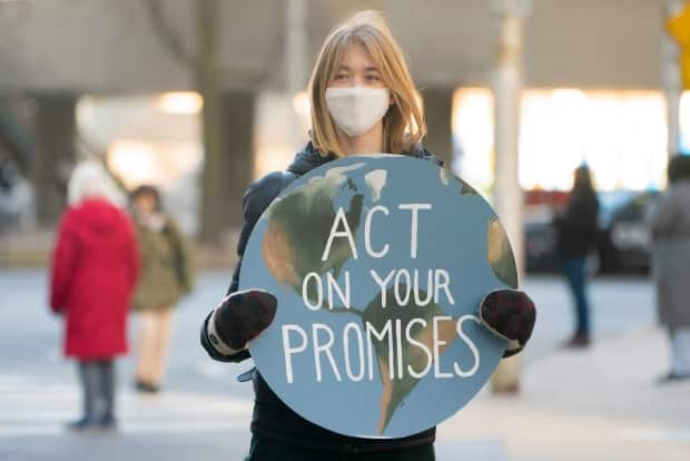 A youth climate protester holds a sign in downtown Toronto on Friday, March 19, 2021.