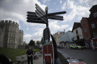 A worker attaches a cutout of a guardsman to a sign to remind people not to let their guard down with regards to coronavirus, to coincide with non-essential shops being reopened this week, outside Windsor Castle, in Windsor, England, Wednesday, April 14, 2021. Britain's Prince Philip, husband of Queen Elizabeth II, died Friday April 9 aged 99. His funeral service will take place on Saturday at Windsor Castle. (AP Photo/Matt Dunham)