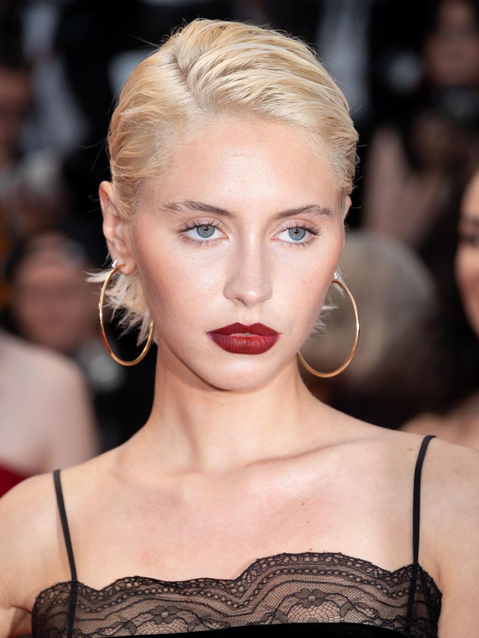 Iris Law with gold hoops and crimson red lipstick