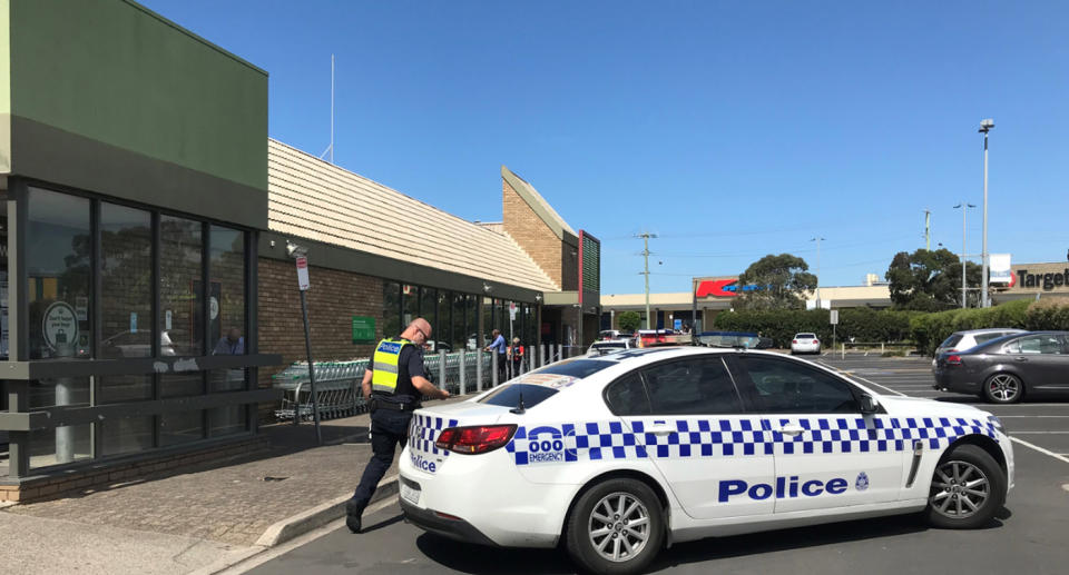 Pictured is a police car and a police officer in the car park of a Woolworths supermarket in Rosebud on the Mornington Peninsula. 