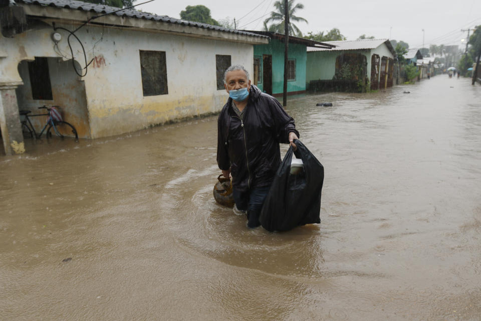 A man walks in knee-deep floodwaters carrying belongings in San Manuel, Honduras, Wednesday, Nov. 4, 2020. Eta weakened from the Category 4 hurricane to a tropical storm after lashing the Caribbean coast for much of Tuesday, its floodwaters isolating already remote communities and setting off deadly landslides. (AP Photo/Delmer Martinez)