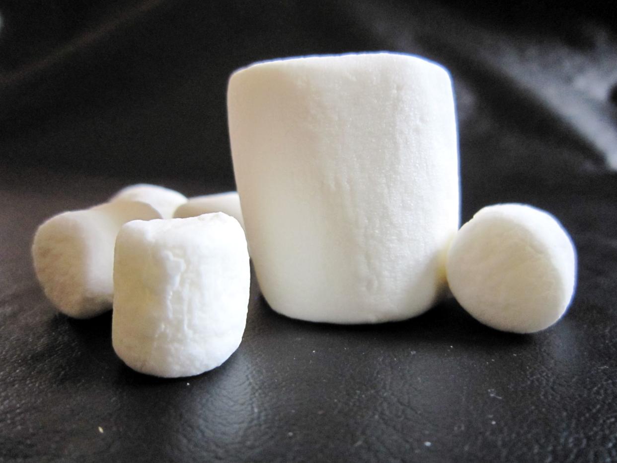 A group of six marshmallows on a black background.