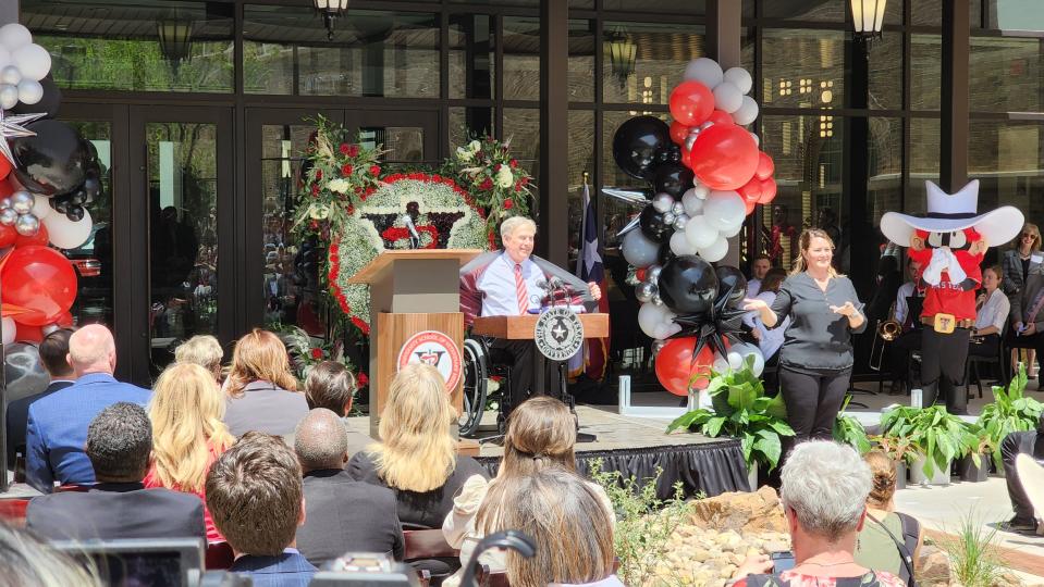 Gov. Greg Abbott shows off his Texas Tech colors Friday as he spoke about the opening of the Texas Tech School of Veterinary Medicine as Raider Red and the crowd look on.