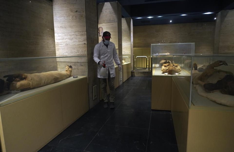 A worker disinfects the Royal Mummies Hall, in an effort to help prevent the spread of the coronavirus, at the Egyptian Museum in Tahrir Square, Cairo, Egypt, Monday, March 23, 2020. (AP Photo/Hamada Elrasam)