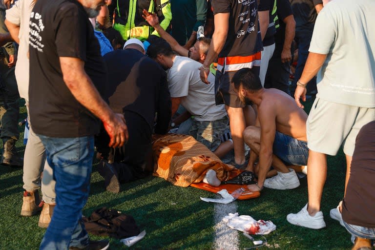 Fuerzas de seguridad israelíes y médicos tratan a una víctima en la cancha de fútbol de Majdal Shams donde cayó un ataque procedente del Líbano. (Photo by Jalaa MAREY / AFP)