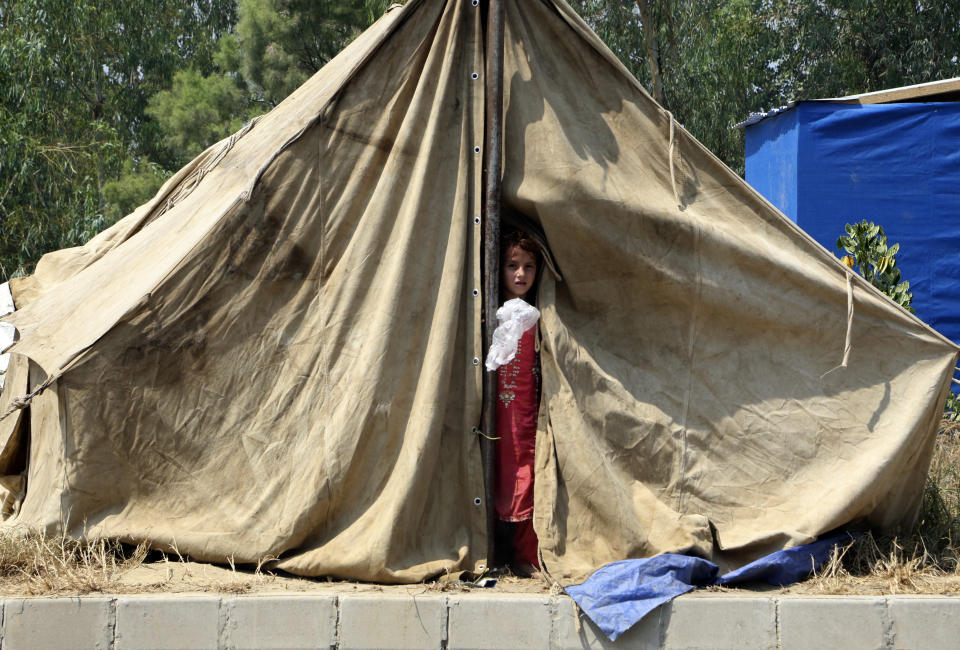 A displaced girl peers from the door of her tent after floodwaters hit her family home, in Charsadda, Pakistan, Wednesday, Aug. 31, 2022. Officials in Pakistan raised concerns Wednesday over the spread of waterborne diseases among thousands of flood victims as flood waters from powerful monsoon rains began to recede in many parts of the country. (AP Photo/Mohammad Sajjad)