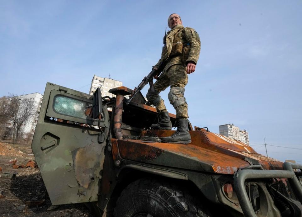 A Ukrainian soldier stands on top of a destroyed Russian APC after recent battle in Kharkiv, Ukraine, Saturday, March 26, 2022 (Efrem Lukatsky/AP/PA) (AP)