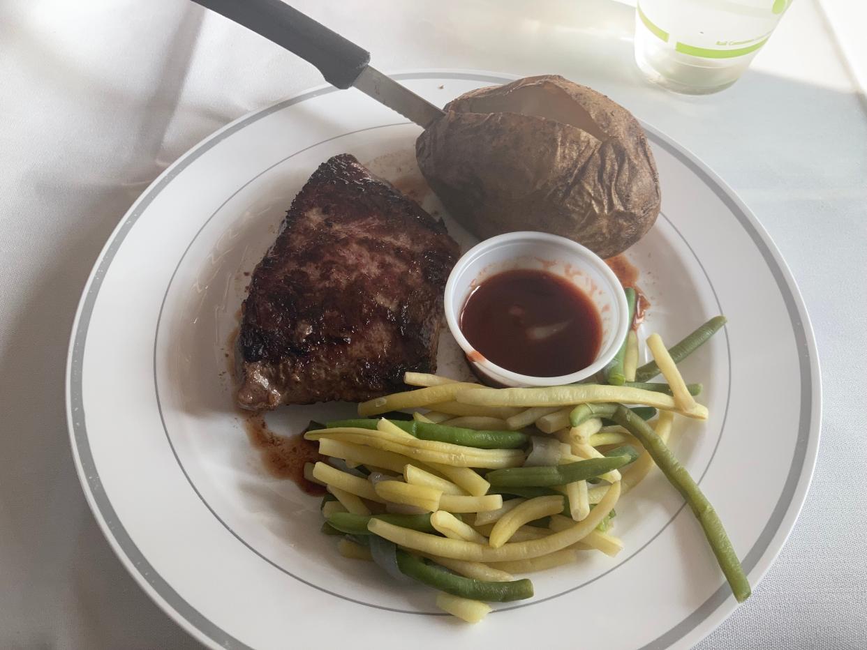 A medium rare steak served with a baked potato, green beans and port wine sauce is one of the dinner entrees available on Amtrak trains. Dinners also come with one complimentary alcoholic beverage, an appetizer and a dessert.