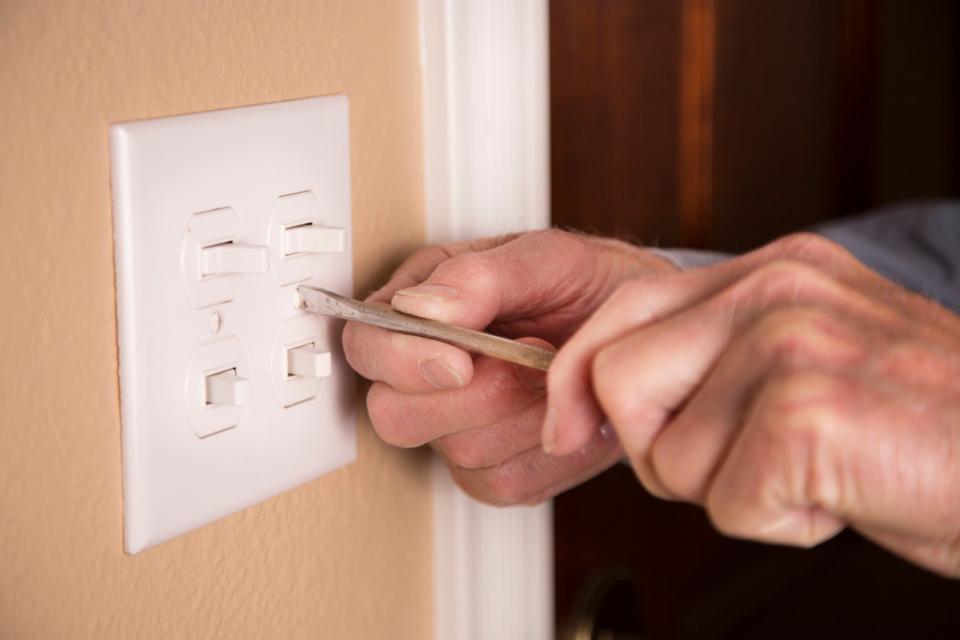 A-pair-of-hands-uses-a-screwdriver-to-install-a-new-switch-plate.