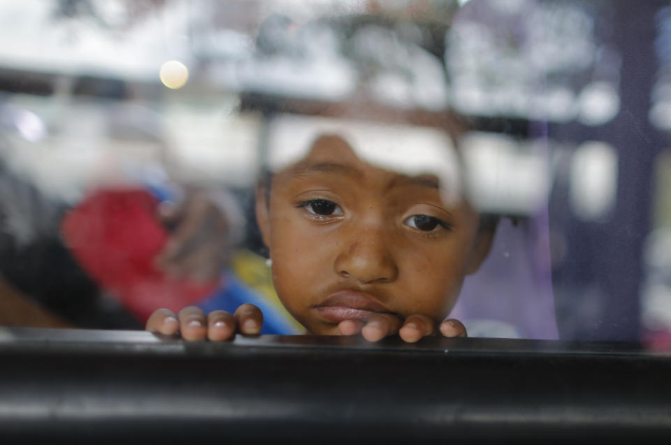 A little girl looks out of a bus window in Caracas, Venezuela, Wednesday, Feb. 19, 2020. The debate over fresh U.S. sanctions aimed at forcing out Venezuela's Nicolás Maduro played out Wednesday across the crisis-stricken South American nation. Families have been split up with at least 4.5 million Venezuelans fleeing crumbling public services. (AP Photo/Ariana Cubillos)