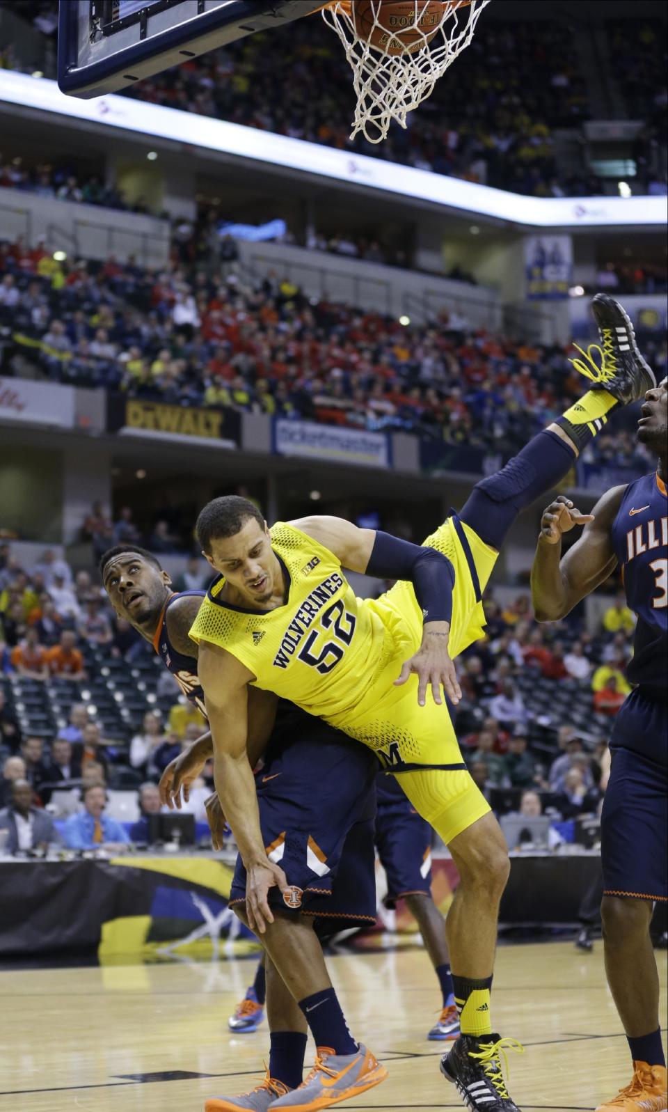 Michigan forward Jordan Morgan falls to the floor after scoring a basket against Illinois guard Rayvonte Rice, left, in the first half of an NCAA college basketball game in the quarter finals of the Big Ten Conference tournament Friday, March 14, 2014, in Indianapolis. (AP Photo/Michael Conroy)
