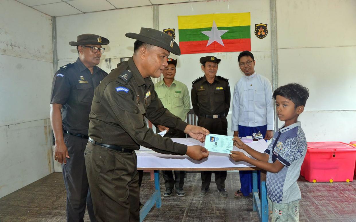 Myanmar immigration official (2nd L) handing over identification documents to an unidentified Rohingya boy - AFP