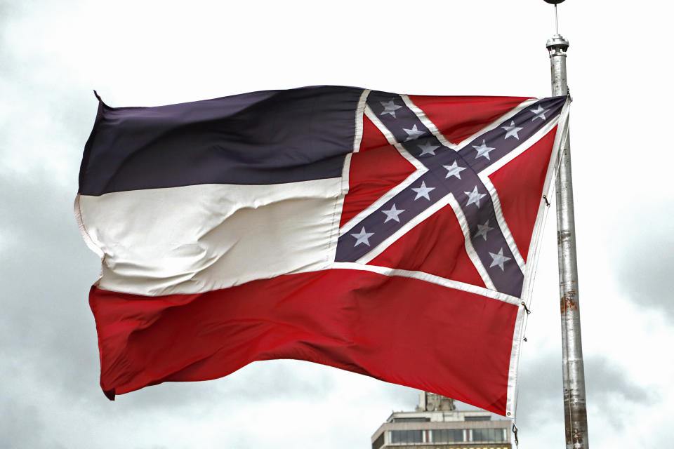 File-This June 25, 2020, file photo shows a Mississippi state flag flying outside the Capitol in Jackson, Miss. Mississippi will surrender the Confederate battle emblem from its state flag, more than a century after white supremacist legislators embedded it there a generation after the South lost the Civil War. Mississippi's House and Senate voted in succession Sunday, June 28, 2020, to retire the flag, with broad bipartisan support. Republican Gov. Tate Reeves has said he will sign the bill, and the state flag would lose its official status as soon as he signs the measure. (AP Photo/Rogelio V. Solis, File)