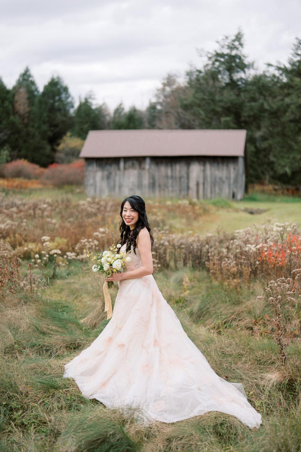 A bride stands in a field wearing a floral-patterned wedding dress.