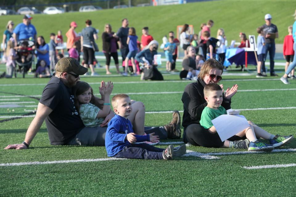 The Smith family, from left, Caleb, Helen, Benny, Lauren and Will applaud while listening to those reading on the scoreboard on May 9 during Reading Under the Lights at Blue Streak Stadium in Lake Township. The event promoted reading and took place on the football field.