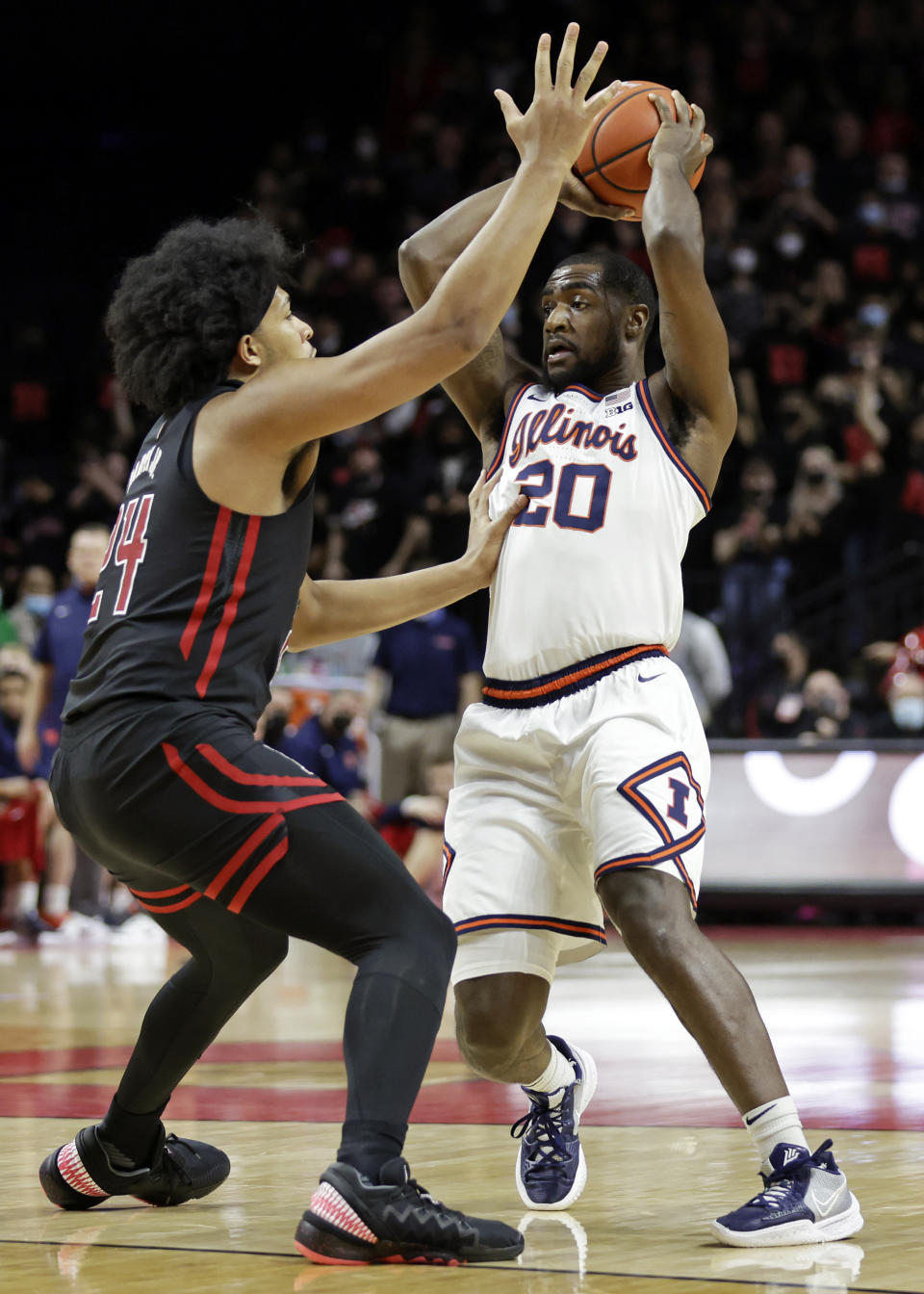 Illinois guard Da'Monte Williams (20) looks to pass the ball as Rutgers forward Ron Harper Jr. defends during the first half of an NCAA college basketball game Wednesday, Feb. 16, 2022, in Piscataway, N.J. (AP Photo/Adam Hunger)