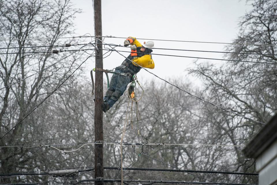 DTE crew work on downed power lines behind houses off of Thomas Avenue in Warren on Monday, Feb. 27, 2023.