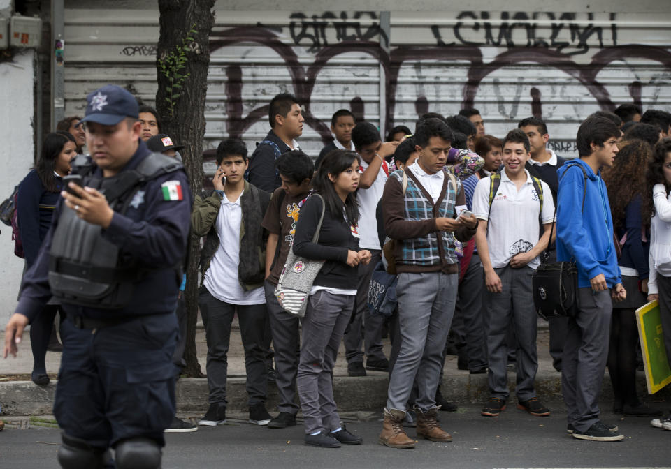 People stand on the side of the street as police try to reopen the street to cars after an earthquake shook Mexico City, Thursday, May 8, 2014. A strong earthquake in southern Guerrero state shook the southern Pacific coast of Mexico and several states, including the capital. (AP Photo/Rebecca Blackwell)