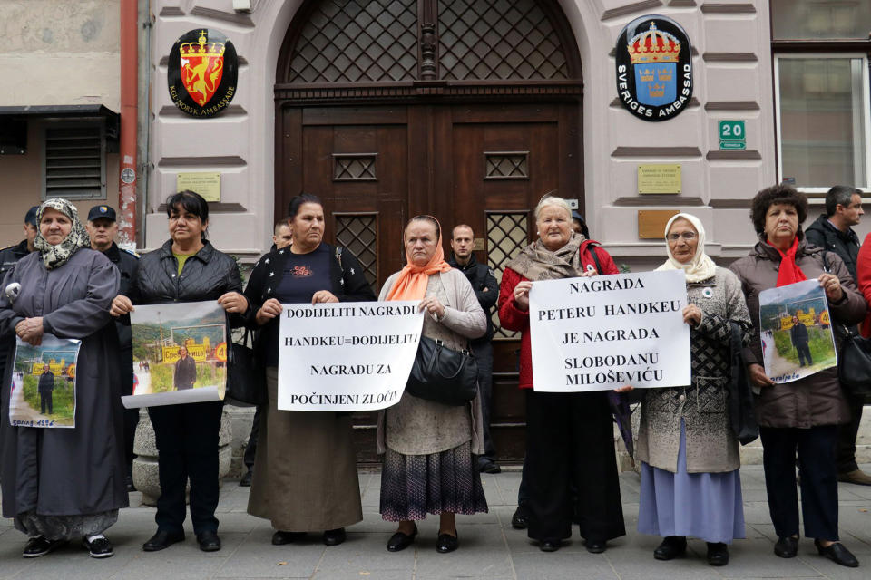 Bosnian women whose male family members, including sons and husbands, perished in the Srebrenica massacre hold placards as they protest outside Swedish embassy in Sarajevo, Bosnia-Herzegovina, Tuesday, Nov. 5, 2019. Several dozen survivors of Bosnia's 1992-95 war staged a protest in Sarajevo to call on the Nobel Committee to reverse its decision to award the 2019 Nobel Prize in literature to Austria's Peter Handke. Placards read: 'to award Handke is equal awarding committed crime' and 'award for Hadke is award for Slobodan Milosevic'. Despite a U.N. court ruling to the contrary, Handke has persistently denied that genocide took place in Srebrenica. (Almir Razic/Fena Agency via AP)