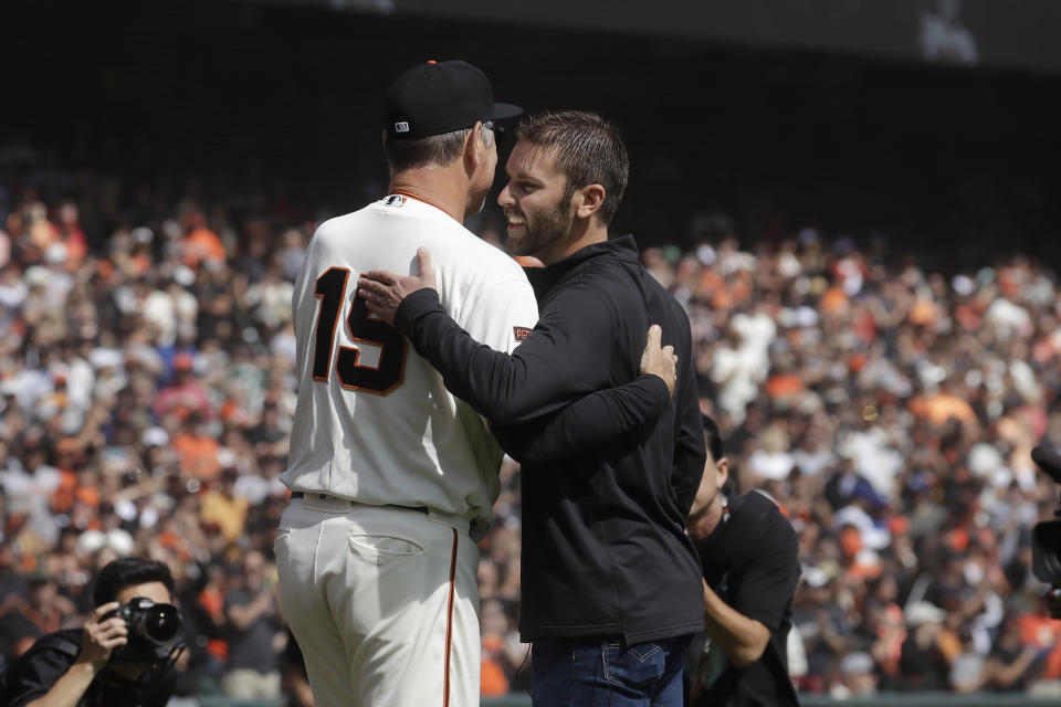 San Francisco Giants manager Bruce Bochy, left, hugs his son, former Giants pitcher Brett Bochy, after the ceremonial first pitch before a baseball game between the Giants and the Los Angeles Dodgers in San Francisco, Sunday, Sept. 29, 2019. (AP Photo/Jeff Chiu)