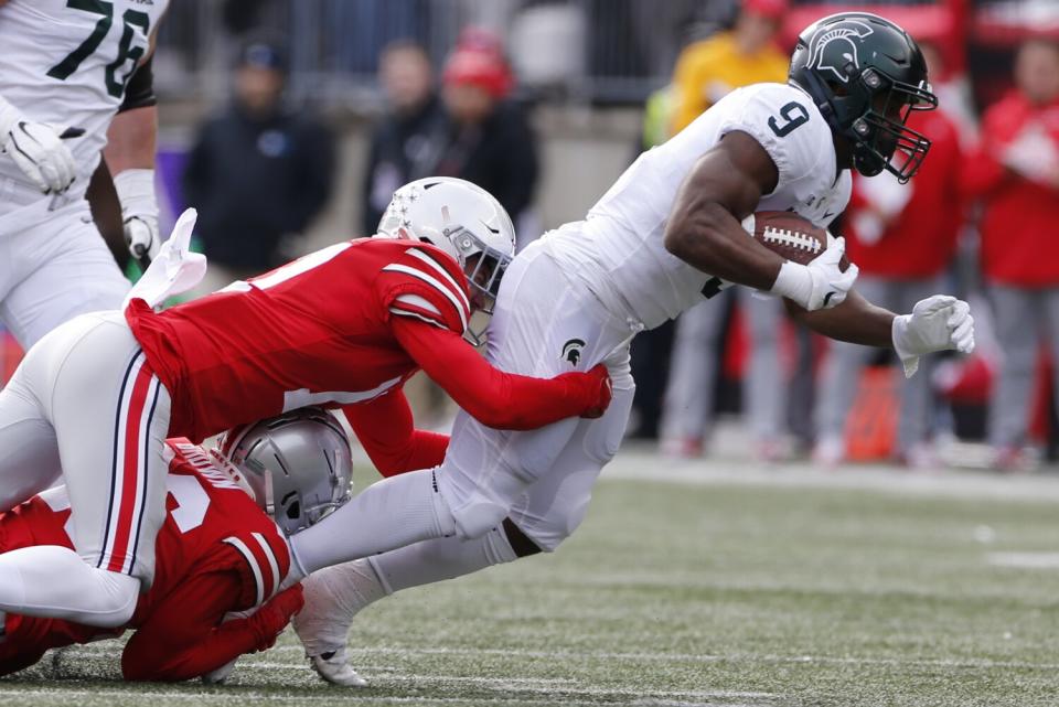 Ohio State defensive back Cameron Brown and defensive back Bryson Shaw tackle Michigan State running back Kenneth Walker.