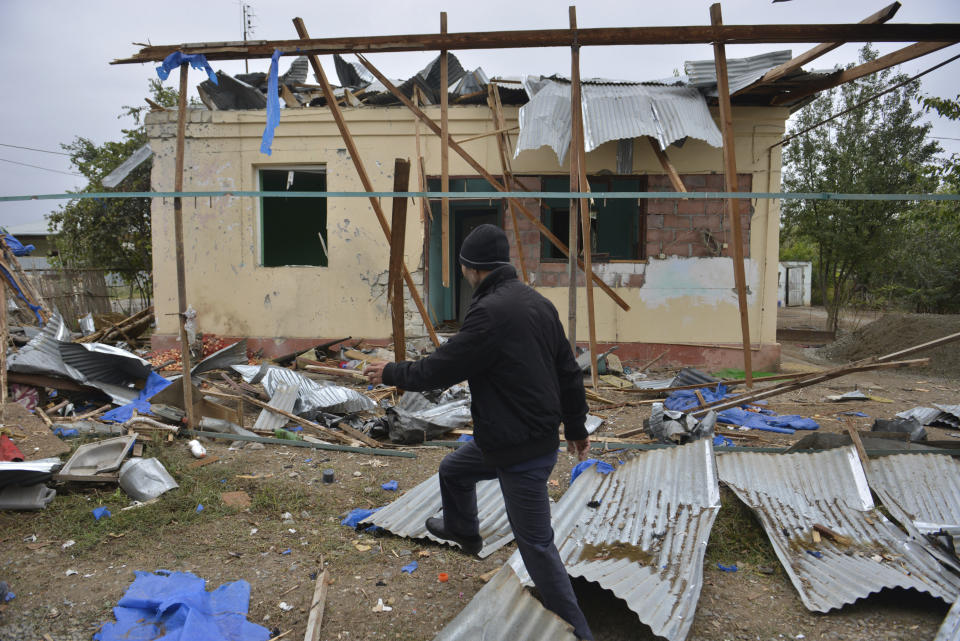 A man walks past a house destroyed by shelling during fighting over the breakaway region of Nagorno-Karabakh in Agdam, Azerbaijan, Thursday, Oct. 1, 2020. Clashes broke out Sunday in Nagorno-Karabakh, a region within Azerbaijan that has been controlled by ethnic Armenian forces backed by the Armenian government since the end of a separatist war a quarter-century ago. Fighting has continued unchecked since then, killing dozens and leaving scores wounded. Armenian and Azerbaijani forces blame each other for continuing attacks. (AP Photo/Aziz Karimov)