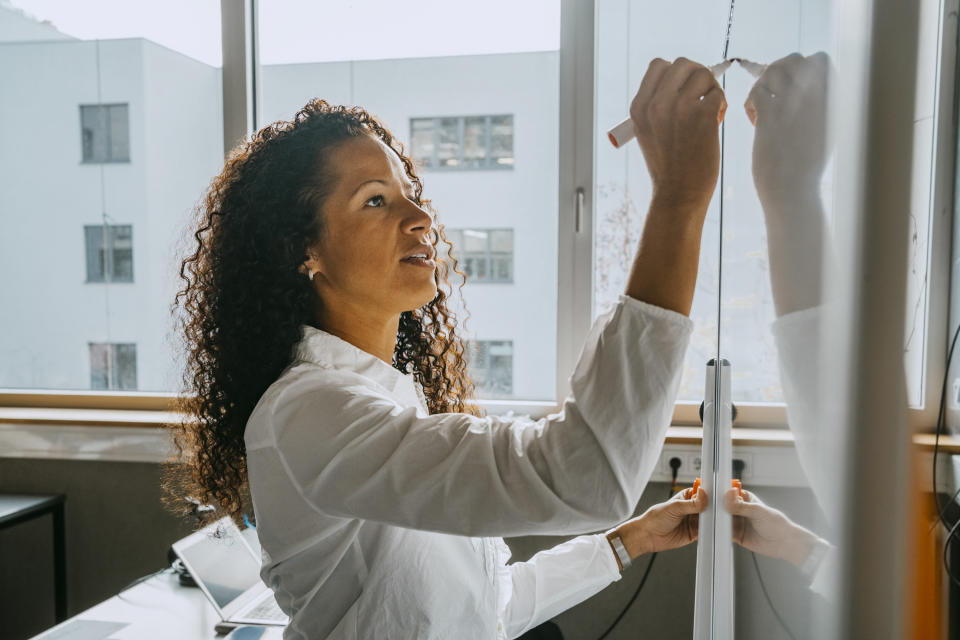 A woman writing on a white board inside a classroom