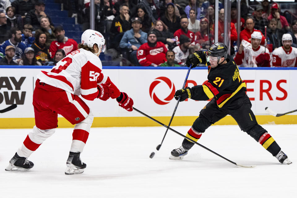 Vancouver Canucks' Nils Hoglander (21) shoots as Detroit Red Wings' Moritz Seider (53) defends during the first period of an NHL hockey game Thursday, Feb. 15, 2024, in Vancouver, British Columbia. (Ethan Cairns/The Canadian Press via AP)