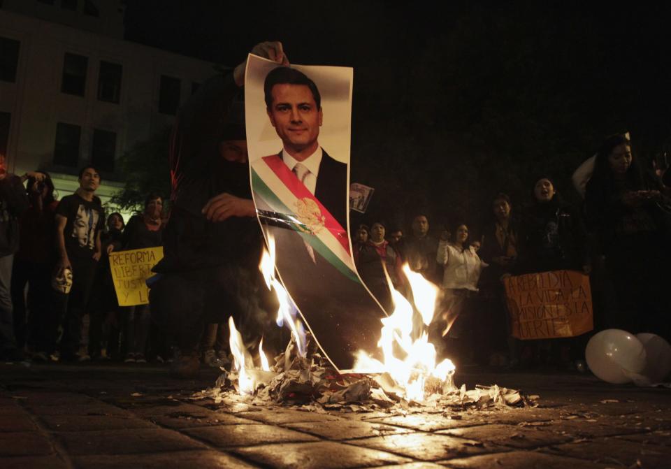 A demonstrator burns a photograph of Mexico's President Enrique Pena Nieto during a protest in support of the 43 missing Ayotzinapa students, in Monterrey