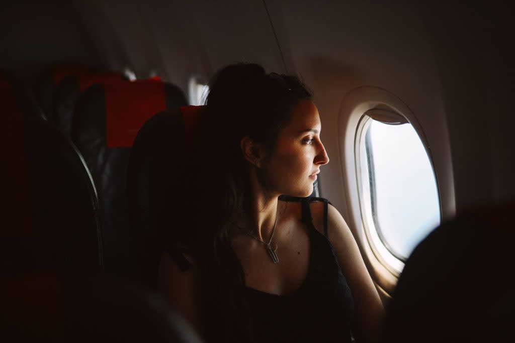 A woman looks out the window as she takes a flight.