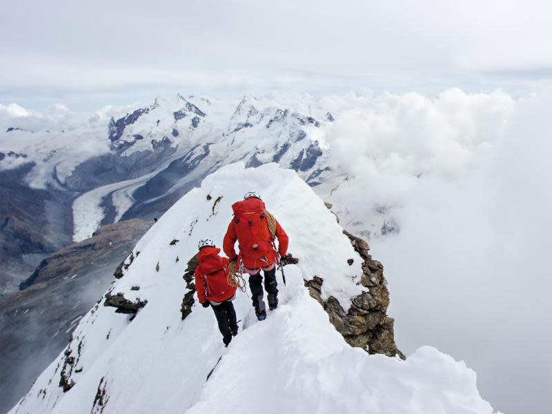 Diese zwei Bergsteiger am Gipfelgrat des Matterhorns tragen moderne Funktionskleidung - die Ausrüstung der Erstbesteiger war dagegen sehr einfach. Foto: Zermatt Tourismus/Christoph Frutiger