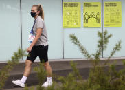 A person walks around Melbourne Park, venue for the Australian Open tennis championships in Melbourne, Australia, Thursday, Feb. 4, 2021. All competition at six Australian Open tuneup events scheduled for Thursday was called off after a worker at one of the tournaments' Melbourne quarantine hotels tested positive for COVID-19.(AP Photo/Hamish Blair)