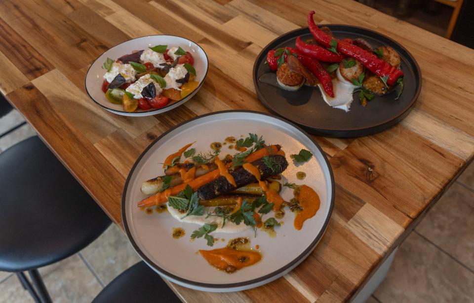 Charred carrots with hummus and harissa (clockwise from bottom), local tomatoes with burrata and basil, and Viking Village scallops with stewed eggplant at Clemmy’s in Waretown.