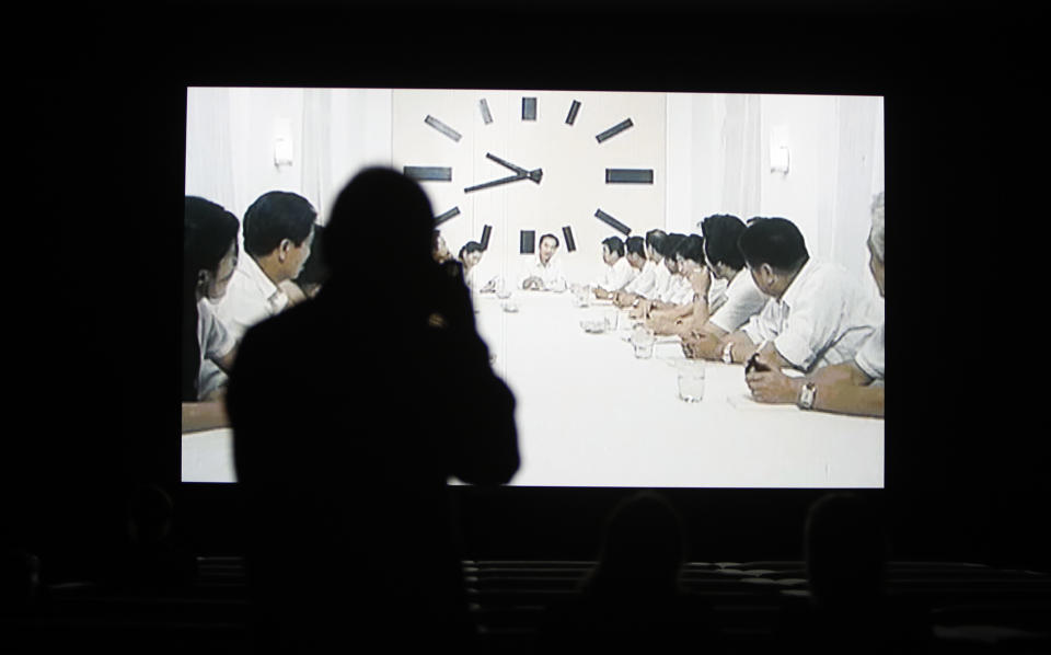 People watch a section of the 24 hour video installation by Christian Marclay entitled ' The Clock' at the Tate Modern in London, Tuesday, Sept. 11, 2018. Christian Marclay's "The Clock" is both the ultimate movie, and an artwork you can set your watch by. The Swiss-American artist has edited together thousands of film clips containing clocks, watches or references to the time _ one or more for every minute of the day _ into a 24-hour video. It’s a mesmerizing patchwork that moves forward in time as it dances back and forth across film history. (AP Photo/Alastair Grant)