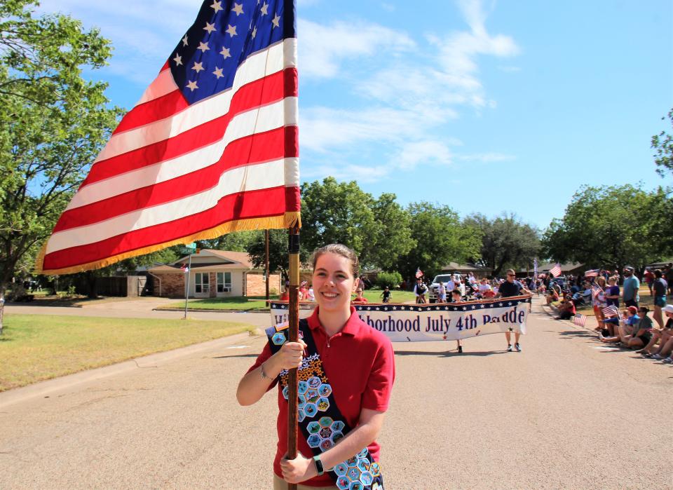 Abigail Songer of Abilene carried the U.S. flag to lead Monday morning's Hillcrest neighborhood parade.