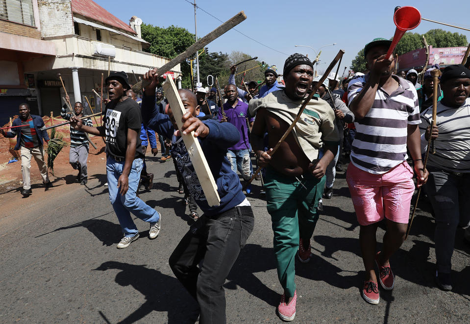 In this photo taken Sunday, Sept. 8, 2019, residents of local hostels march with homemade weapons in Johannesburg. South African police say that two more people have been killed in Johannesburg, bringing to 12 the number of deaths since violence against foreign-owned shops erupted last month. (AP Photo)