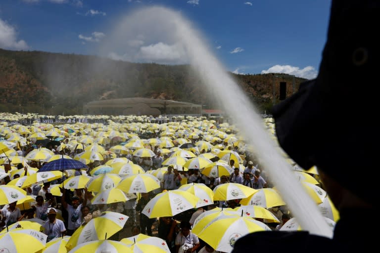 A firefighter sprays water on Catholic faithful gathered for the pope's holy mass (Willy Kurniawan)