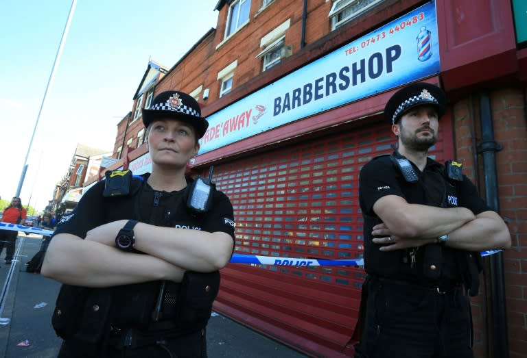 Police officers stand on duty outside the Fade Away barber shop in Moss Side, Manchester, on May 26, 2017, following an early morning raid as part of investigations into the terror attack at Manchester Arena