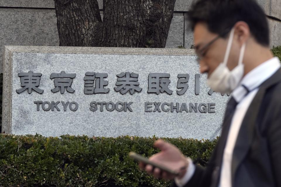 A person walks in front of Tokyo Stock Exchange sign Thursday, Dec. 21, 2023, in Tokyo. Asian shares fell Thursday after Wall Street hit the brakes on its big rally following disappointing corporate profit reports and warnings that the market had surged too far, too fast.(AP Photo/Eugene Hoshiko)