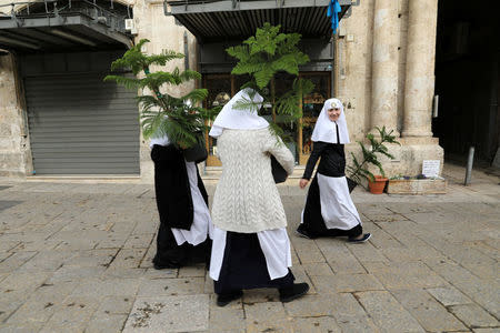 Nuns carry Christmas trees, handed out annually by the Jerusalem municipality, in Jerusalem's Old City December 21, 2017. REUTERS/Ammar Awad