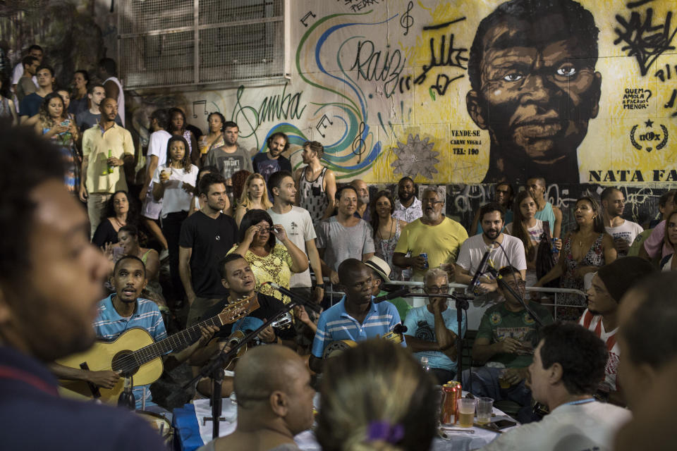 In this March 29, 2016 photo, people listen to live samba music at Pedra do Sal in Rio de Janeiro. A mural in the background features a portrait of Zumbi dos Palmares. (Photo: ASSOCIATED PRESS)