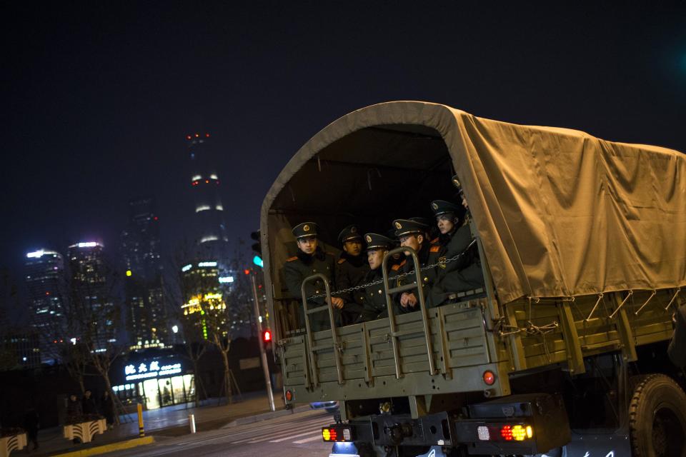 Paramilitary police officers sit on a truck leaving the location where people were killed in a stampede incident during a New Year's celebration on the Bund, in Shanghai