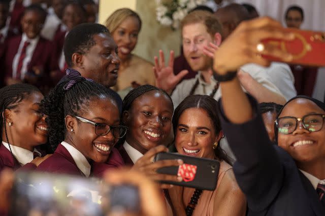 <p>KOLA SULAIMON/AFP via Getty</p> Meghan Markle (center) takes selfie with students at Lightway Academy