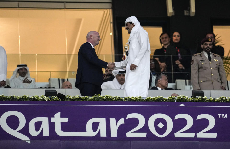 FILE - Emir of Qatar Tamim bin Hamad Al Thani, right, shakes hands with FIFA President Giovanni Infantino, left, prior the World Cup, group A soccer match between Qatar and Ecuador at the Al Bayt Stadium in Al Khor, Sunday, Nov. 20, 2022. Qatar became the first host nation in World Cup history to lose the opening match, and then only the second host to be eliminated from the group stage. South Africa in 2010 was the first host nation to be eliminated in group stage but still had a chance to advance in its third and final group match. (AP Photo/Natacha Pisarenko, File)