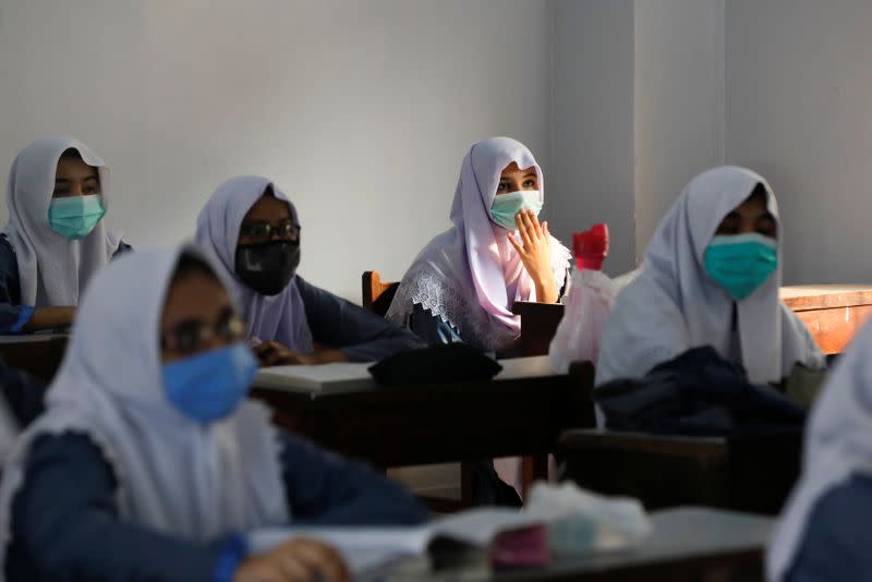 Students wear protective masks while maintaining safe distance as they attend a class as schools reopen amid the coronavirus disease (COVID-19) pandemic, in Karachi,