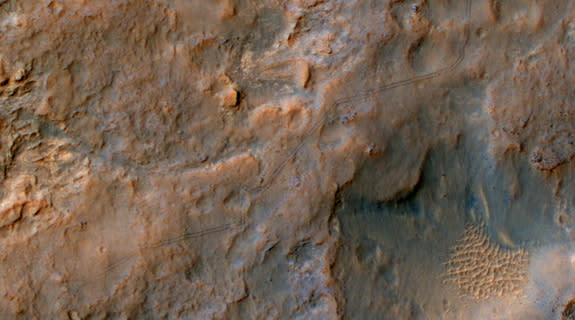 Two parallel tracks left by the- wheels of NASA's Curiosity Mars rover cross rugged ground in this portion of a Dec. 11, 2013, observation by the High Resolution Imaging Science Experiment (HiRISE) camera on NASA's Mars Reconnaissance Orbiter.