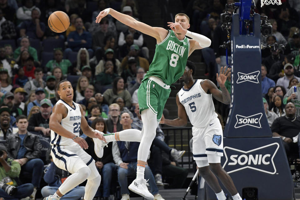 Boston Celtics center Kristaps Porzingis (8) passes the ball away from Memphis Grizzlies guards Vince Williams Jr. (5) and Desmond Bane (22) in the first half of an NBA basketball game Sunday, Nov. 19, 2023, in Memphis, Tenn. (AP Photo/Brandon Dill)