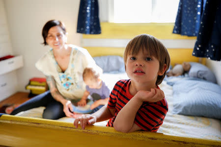 Three and a half year old Wyatt Gries (R) poses on his bed inside his bedroom while his mother Amanda Gries holds his 12 month old brother Eli Gries in the Del Rey neighborhood of Los Angeles, California, United States April 4, 2017. REUTERS/Danny Moloshok