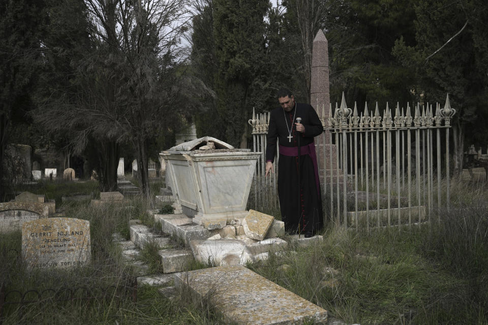 Hosam Naoum, a Palestinian Anglican bishop, points to a damaged grave where vandals desecrated more than 30 graves at a historic Protestant Cemetery on Jerusalem's Mount Zion in Jerusalem, Wednesday, Jan. 4, 2023. Israel's foreign ministry called the attack an "immoral act" and "an affront to religion." Police officers were sent to investigate the profanation. (AP Photo/ Mahmoud Illean)